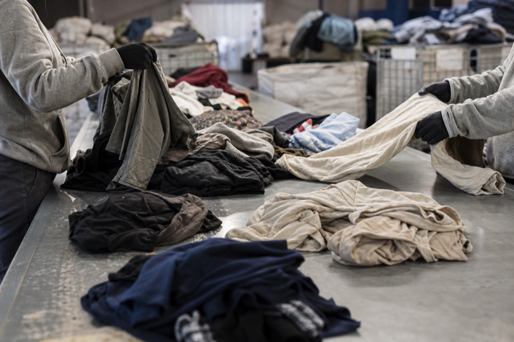 Staff sorting and grading used clothing by quality on an inspection table