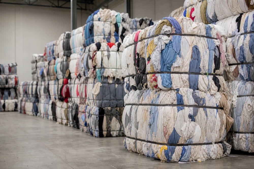 Compressed bales of mixed industrial wiper rags in the recycling warehouse